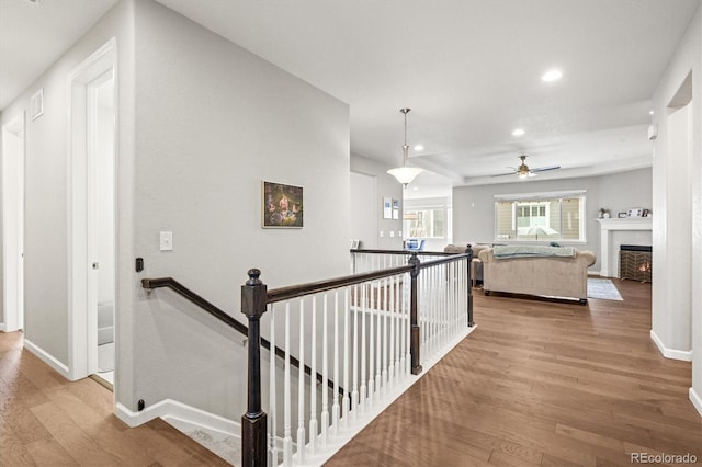 corridor featuring recessed lighting, baseboards, an upstairs landing, and wood finished floors