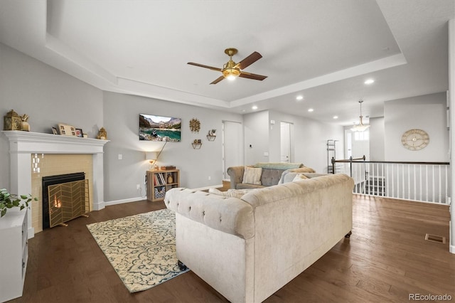 7268 Greenwater Cir, Castle Rock, CO 80108 - living room with a tray ceiling, a tiled fireplace, dark wood finished floors, and recessed lighting