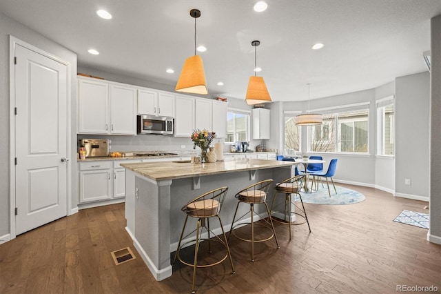 7268 Greenwater Cir, Castle Rock, CO 80108 - kitchen with stainless steel appliances, dark wood-type flooring, a kitchen island, visible vents, and white cabinets