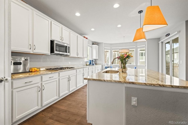 7268 Greenwater Cir, Castle Rock, CO 80108 - kitchen with dark wood-style floors, stainless steel appliances, white cabinets, a sink, and an island with sink