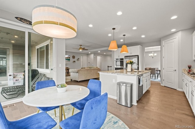 7268 Greenwater Cir, Castle Rock, CO 80108 - dining space featuring light wood-type flooring, visible vents, ceiling fan with notable chandelier, and recessed lighting