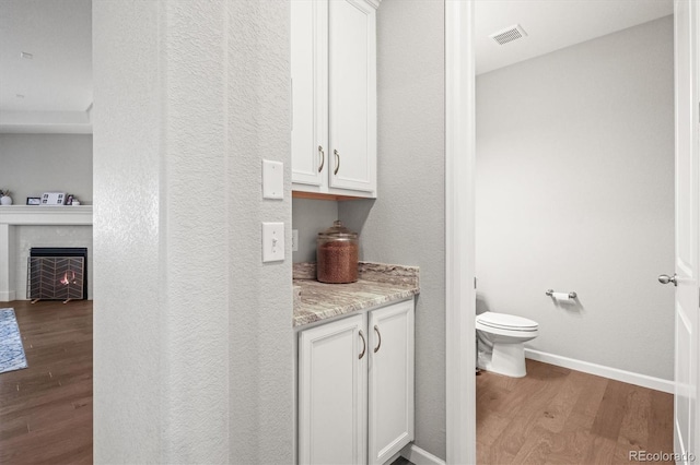 7268 Greenwater Cir, Castle Rock, CO 80108 - bathroom with a fireplace, visible vents, toilet, wood finished floors, and baseboards