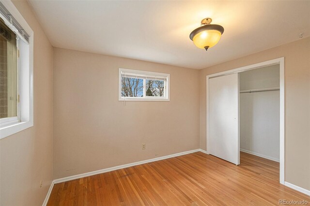 unfurnished bedroom with light wood-type flooring and a closet