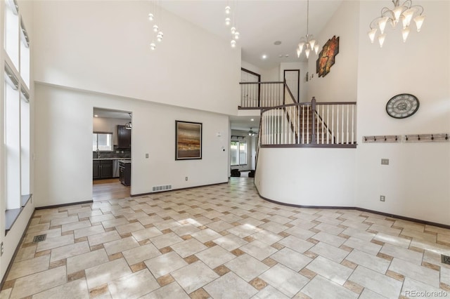 13486 Clayton St, Thornton, CO 80241 - unfurnished living room with a towering ceiling, a chandelier, stairs, and light tile patterned floors