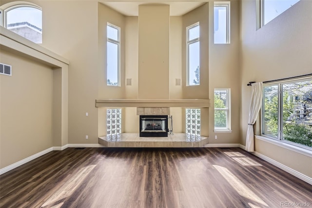 2950 Wyecliff Ln, Highlands Ranch, CO 80126 - unfurnished living room with a high ceiling, baseboards, dark wood finished floors, and a tile fireplace