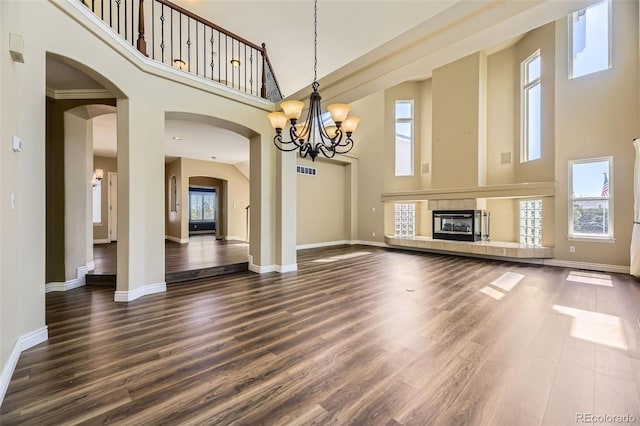 2950 Wyecliff Ln, Highlands Ranch, CO 80126 - unfurnished living room featuring a towering ceiling, a chandelier, dark wood-type flooring, baseboards, and arched walkways