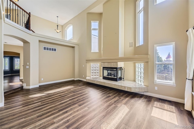 2950 Wyecliff Ln, Highlands Ranch, CO 80126 - unfurnished living room with a high ceiling, wood finished floors, baseboards, arched walkways, and a tiled fireplace