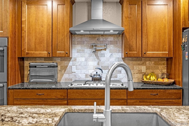 459 County Road 85, Guffey, CO 80820 - kitchen with wall chimney range hood, brown cabinetry, and tasteful backsplash