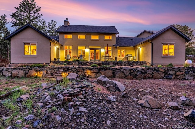 459 County Road 85, Guffey, CO 80820 - back of house at dusk featuring a chimney, french doors, and stucco siding