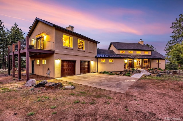 459 County Road 85, Guffey, CO 80820 - view of front facade with a chimney, a standing seam roof, concrete driveway, an attached garage, and covered porch