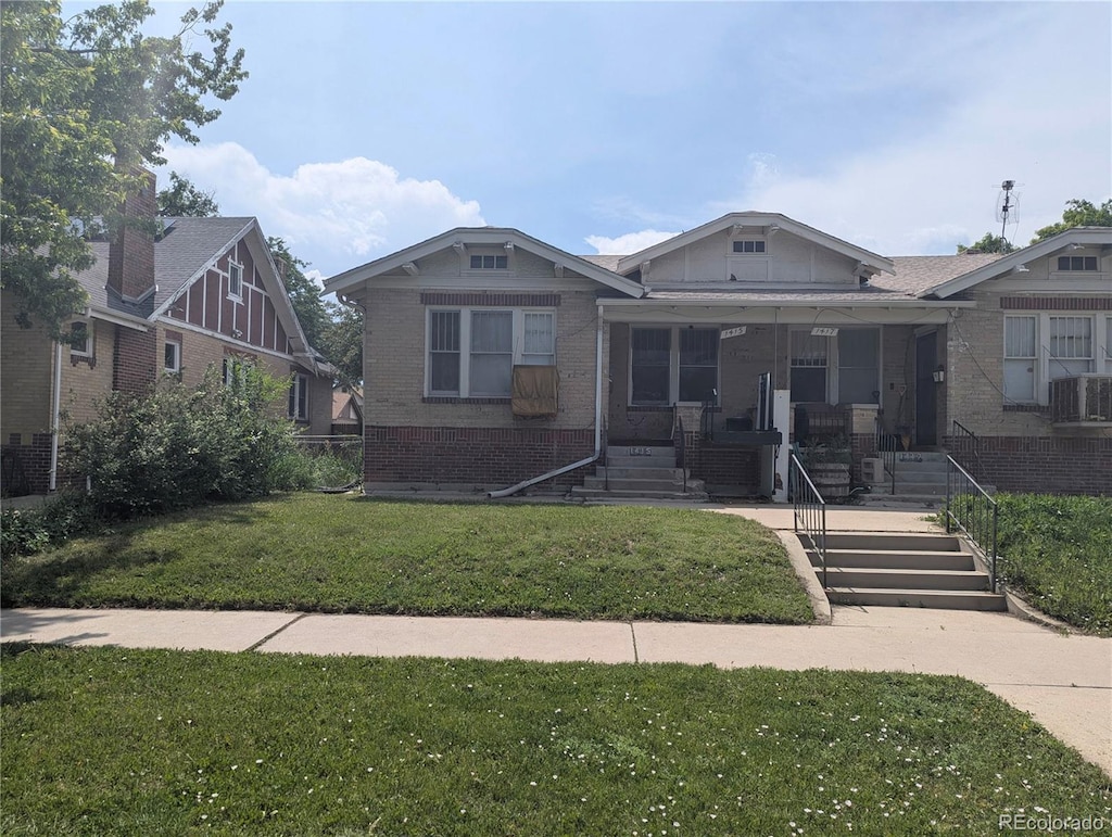 1415 Raleigh St, Denver, CO 80204 - bungalow featuring brick siding, a front lawn, covered porch, and stairs