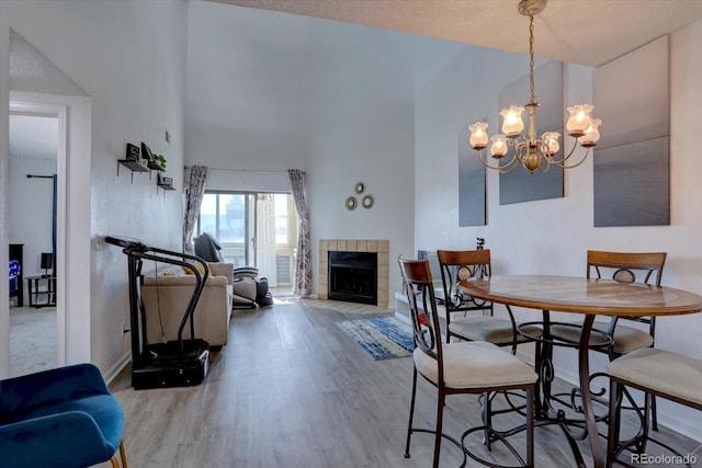11115 E Alameda Ave Unit 201, Aurora, CO 80012 - dining area with a towering ceiling, a fireplace, wood finished floors, baseboards, and a notable chandelier