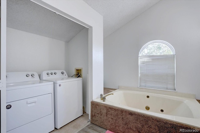 11115 E Alameda Ave Unit 201, Aurora, CO 80012 - bathroom featuring independent washer and dryer, a textured ceiling, tile patterned floors, a tub with jets, and lofted ceiling