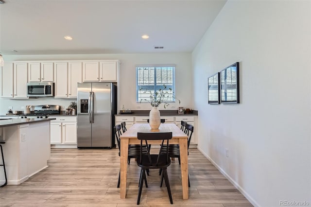 kitchen with white cabinets, light hardwood / wood-style floors, and appliances with stainless steel finishes