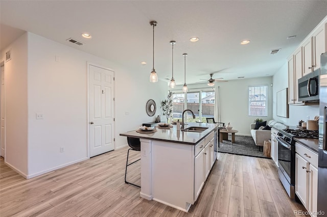 kitchen featuring white cabinetry, sink, stainless steel appliances, an island with sink, and light wood-type flooring