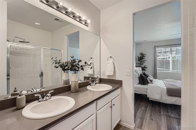 bathroom featuring hardwood / wood-style floors, vanity, a textured ceiling, and walk in shower