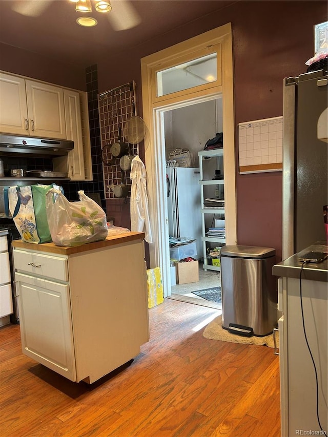 36 N Logan St, Denver, CO 80203 - kitchen with under cabinet range hood, light wood-style floors, white cabinetry, and backsplash