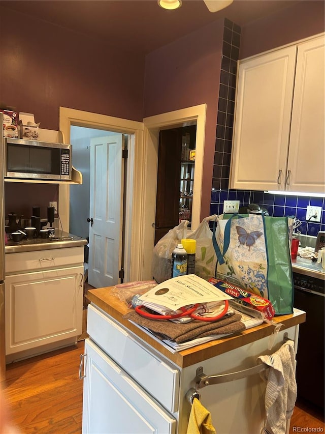 36 N Logan St, Denver, CO 80203 - kitchen with stainless steel microwave, white cabinetry, light wood finished floors, backsplash, and black dishwasher