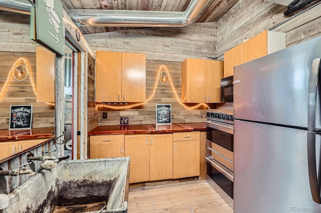 6646 S Fundy Ct, Centennial, CO 80016 - kitchen with stainless steel appliances, wooden walls, light wood-style floors, a sink, and dark countertops