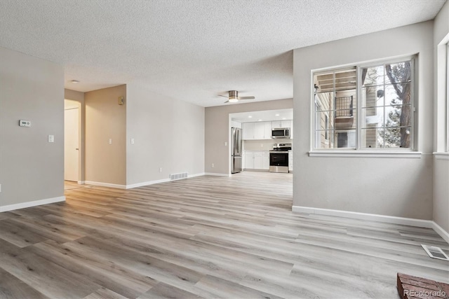 unfurnished living room with ceiling fan, a textured ceiling, and light hardwood / wood-style flooring