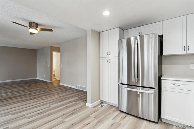 kitchen featuring white cabinetry, ceiling fan, light hardwood / wood-style flooring, stainless steel fridge, and a textured ceiling