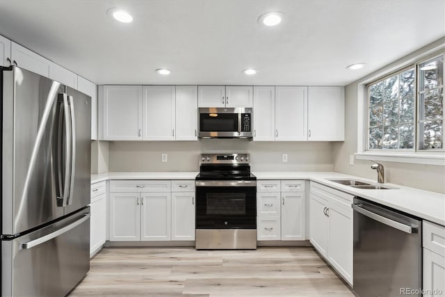 kitchen featuring white cabinets, appliances with stainless steel finishes, light hardwood / wood-style flooring, and sink