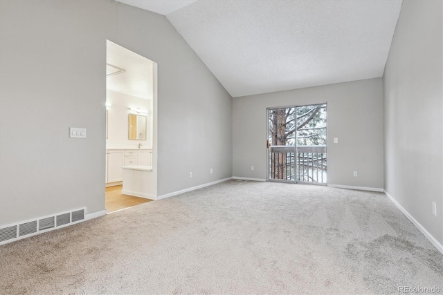 carpeted empty room with a textured ceiling and vaulted ceiling