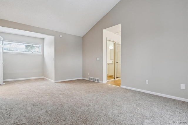 carpeted spare room featuring lofted ceiling