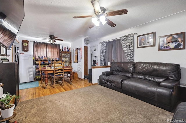 living room with a textured ceiling, light hardwood / wood-style floors, and ceiling fan