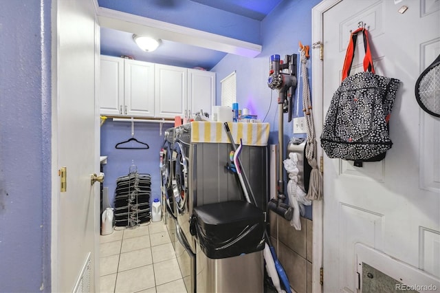 laundry room featuring washer and dryer, light tile patterned floors, and cabinets