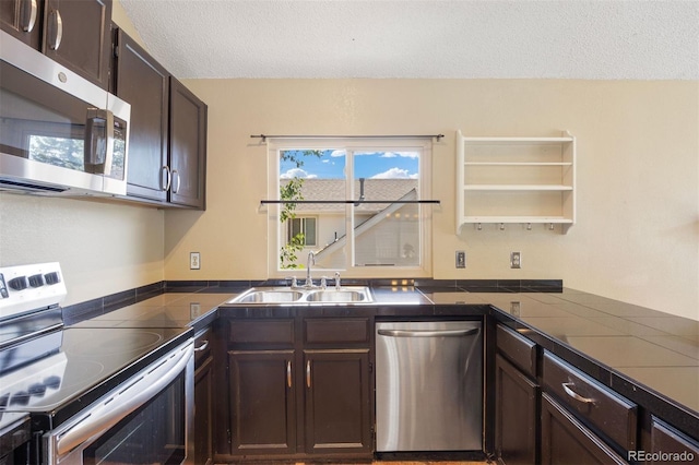 4786 S Yampa St, Aurora, CO 80015 - kitchen with stainless steel appliances, dark countertops, dark brown cabinets, healthy amount of natural light, and a textured ceiling