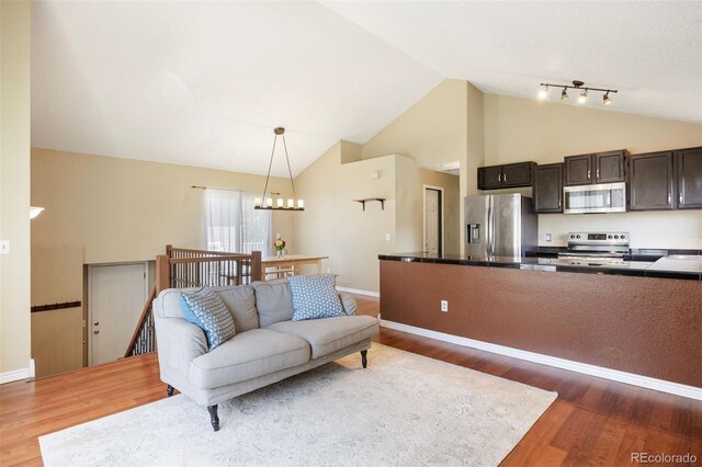 4786 S Yampa St, Aurora, CO 80015 - living room with wood finished floors, lofted ceiling, and a chandelier