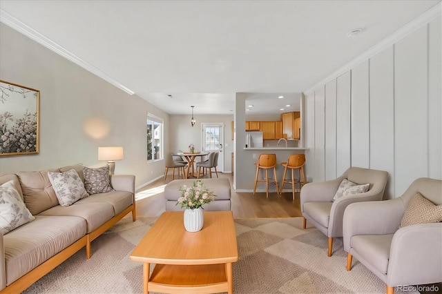 living room with sink, light wood-type flooring, and crown molding