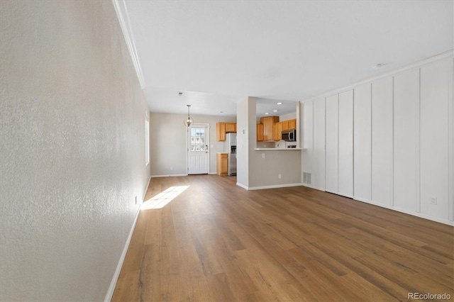 unfurnished living room with crown molding and hardwood / wood-style flooring