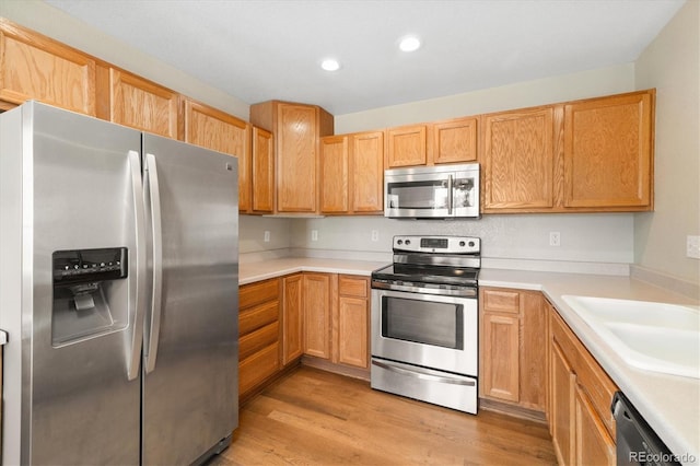 kitchen featuring appliances with stainless steel finishes, light hardwood / wood-style floors, and sink