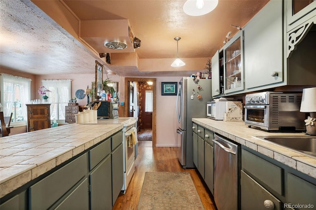 715 Main St, Georgetown, CO 80444 - kitchen featuring appliances with stainless steel finishes, light wood-type flooring, a textured ceiling, glass insert cabinets, and hanging light fixtures