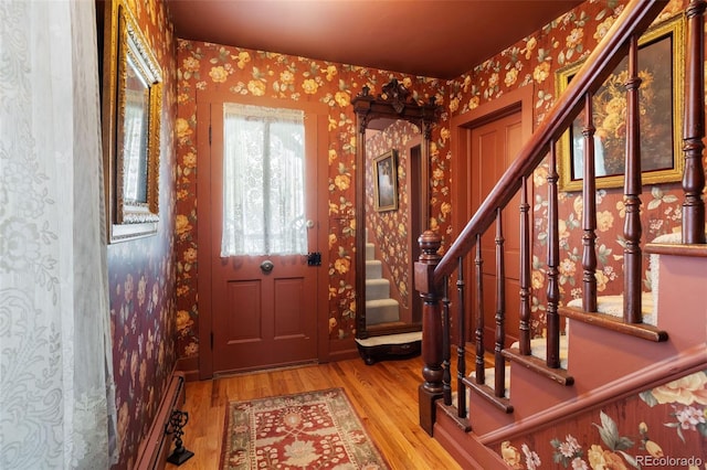 715 Main St, Georgetown, CO 80444 - foyer entrance with wallpapered walls, stairway, wood finished floors, and a baseboard heating unit