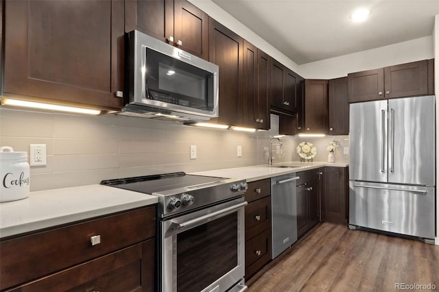 kitchen with sink, stainless steel appliances, dark hardwood / wood-style floors, backsplash, and dark brown cabinets