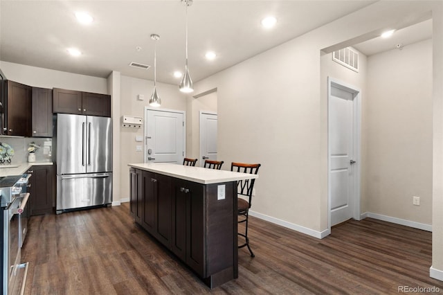 kitchen featuring pendant lighting, backsplash, appliances with stainless steel finishes, a kitchen island, and a breakfast bar area