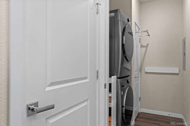 laundry room with dark hardwood / wood-style flooring, electric panel, and stacked washer / dryer