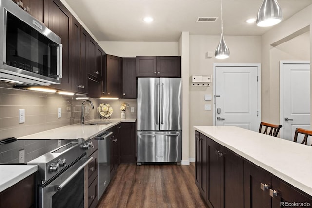 155 S Monaco Pkwy Unit 114, Denver, CO 80224 - kitchen with dark brown cabinets, visible vents, a sink, light countertops, and appliances with stainless steel finishes