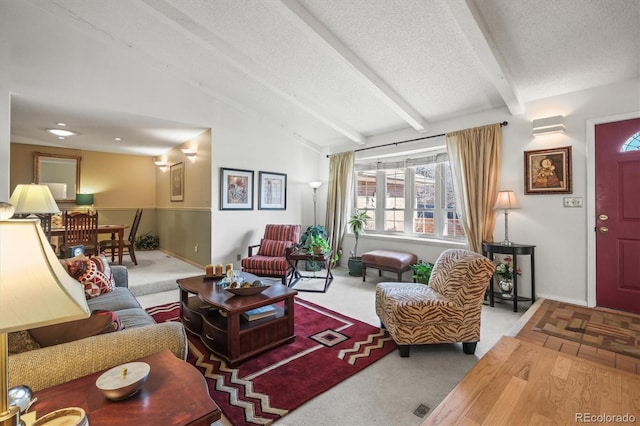 carpeted living area featuring vaulted ceiling with beams, a textured ceiling, and baseboards