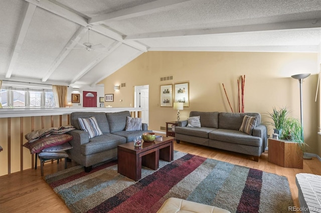 living room featuring visible vents, lofted ceiling with beams, a ceiling fan, a textured ceiling, and wood finished floors