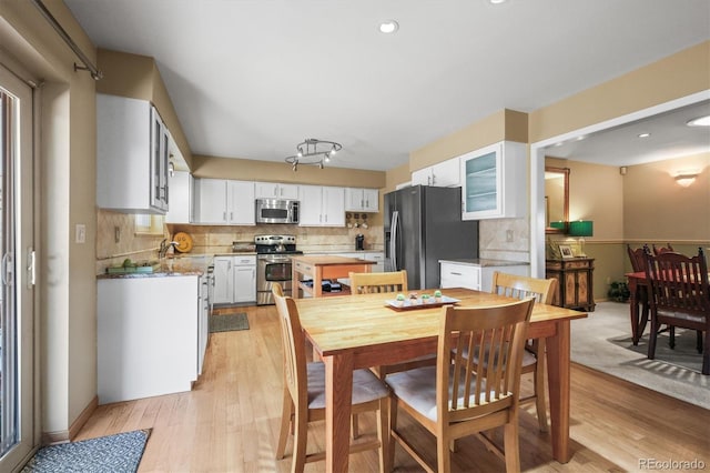 kitchen featuring white cabinets, light wood-type flooring, glass insert cabinets, and stainless steel appliances