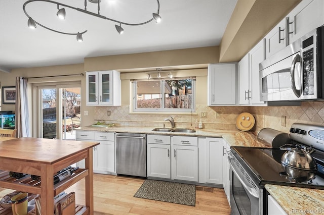 kitchen with stainless steel appliances, a healthy amount of sunlight, a sink, and light wood finished floors