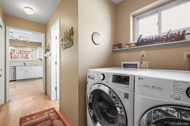 clothes washing area with light wood-style floors, laundry area, and separate washer and dryer