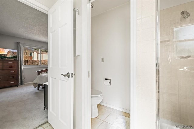 ensuite bathroom with ensuite bathroom, a stall shower, toilet, and tile patterned floors