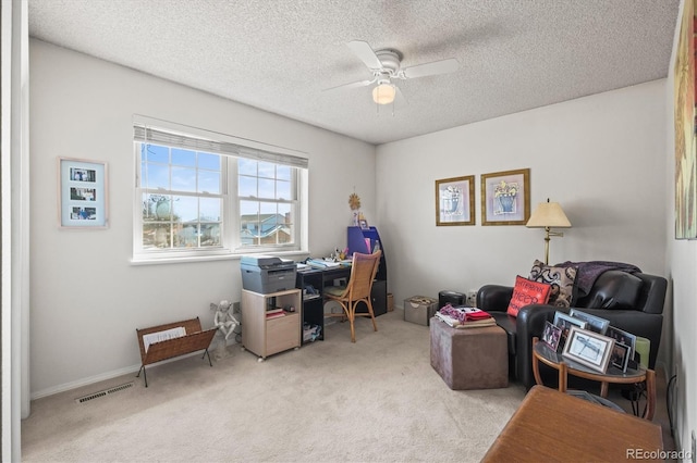 office space featuring carpet floors, a textured ceiling, visible vents, and a ceiling fan