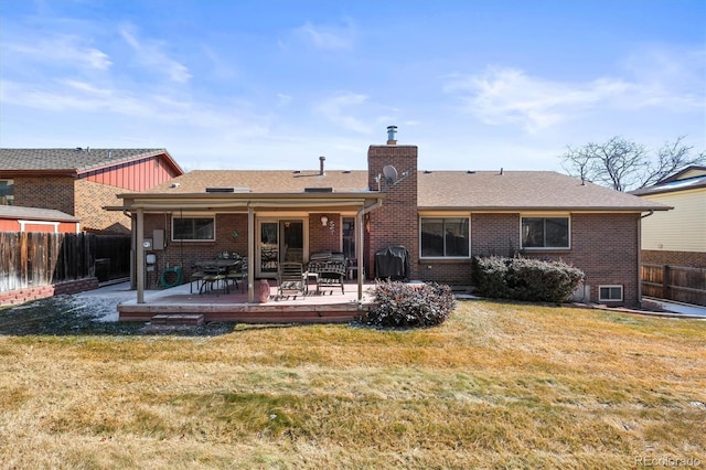 back of property with a yard, brick siding, a chimney, and fence