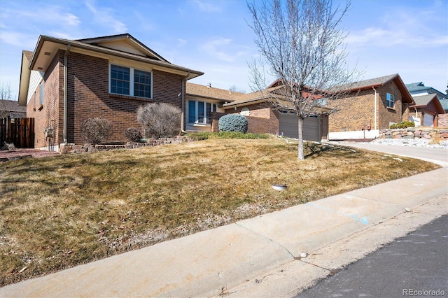 view of front facade with an attached garage, driveway, a front lawn, and brick siding